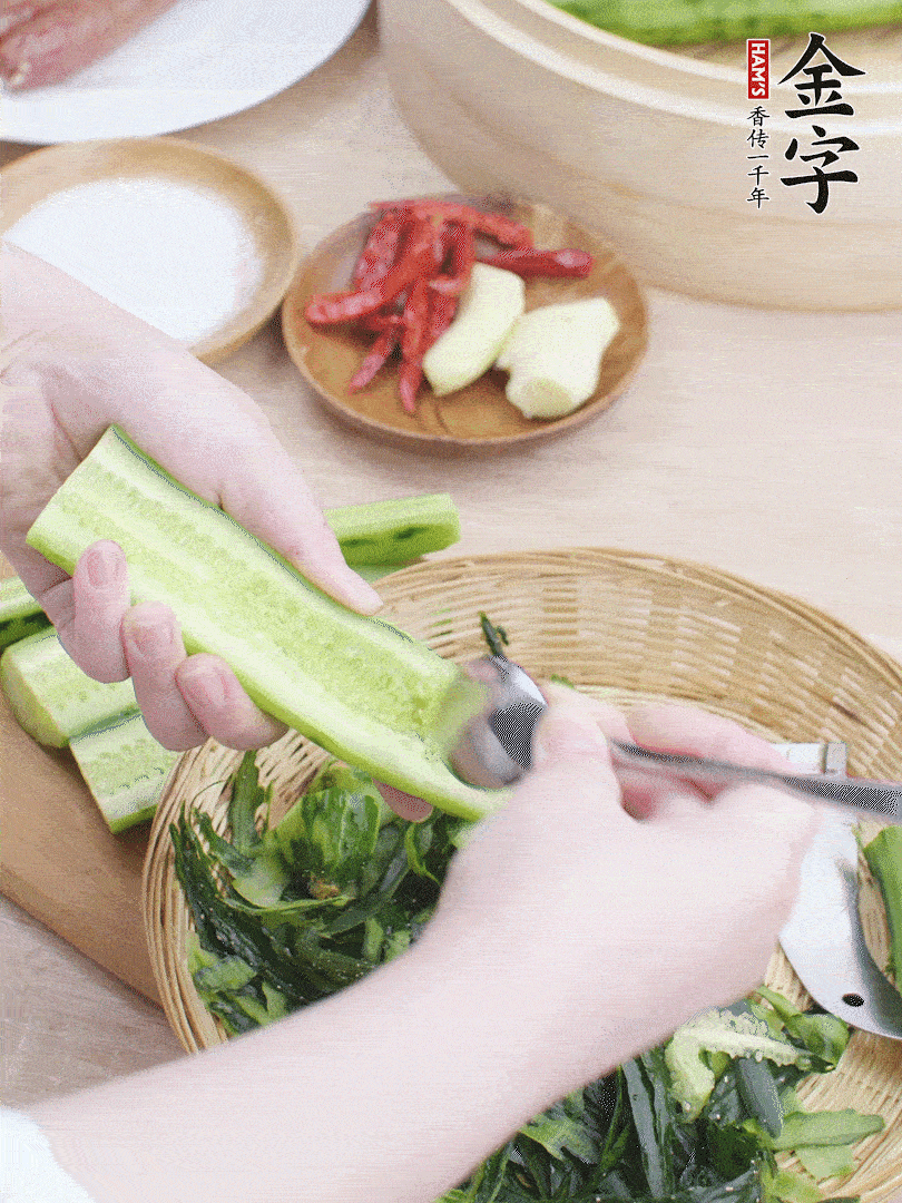 黃瓜削皮，對半切開，勺子挖去內(nèi)瓤，斜刀切片。青蒜斜刀切段。